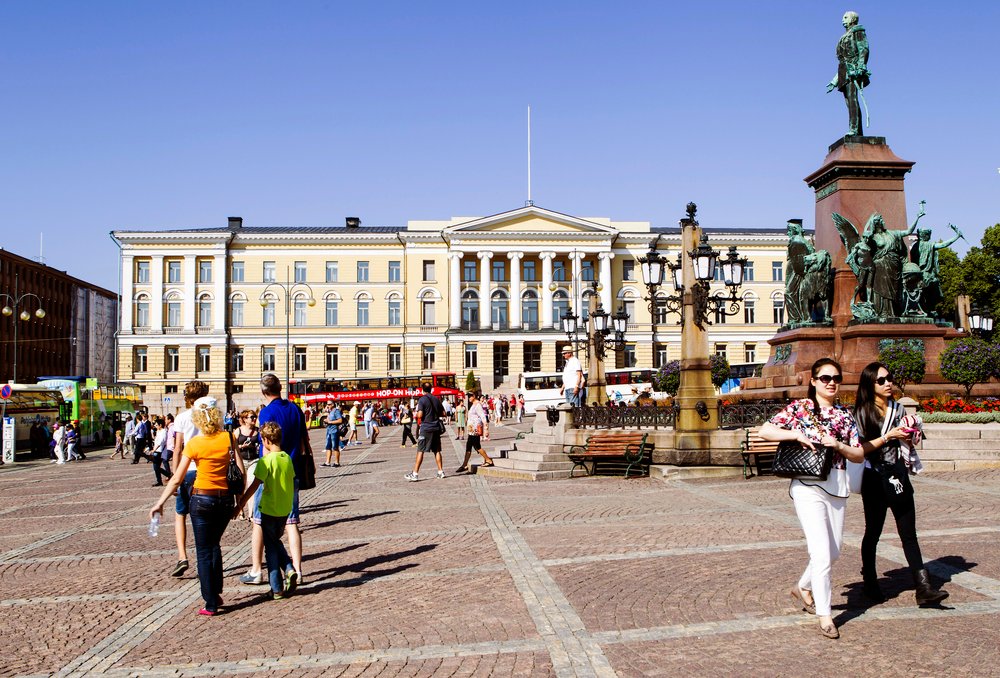 Kuva Senaatinorilta. Taustalla Helsingin yliopiston keltainen päärakennus, oikeassa reunassa patsas, etualalla käveleviä ihmisiä.